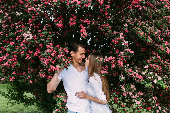 novios posando junto con un arbol con lindas flores