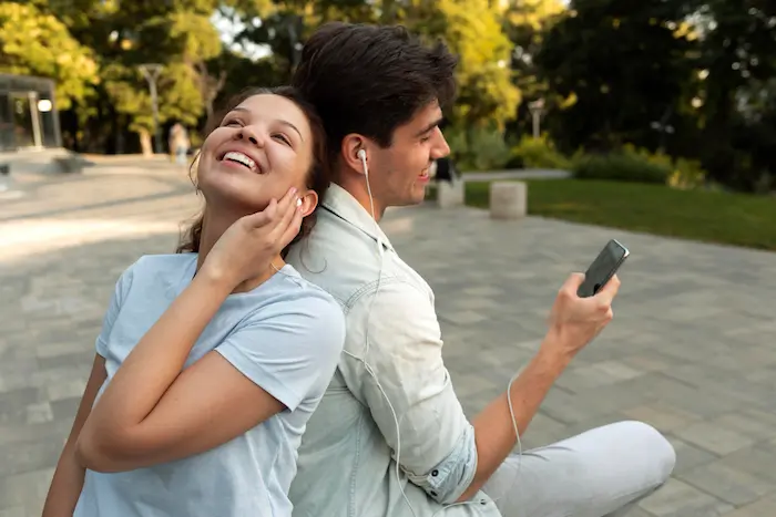 un chico y una chica escuchando música en un parque