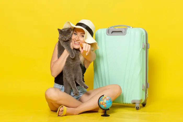 chica con su gato y una maleta amarilla, lista para viajar con mascotas