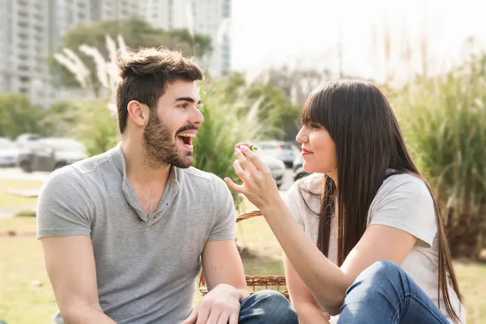 chico haciendo reir a una chica sentados en un parque