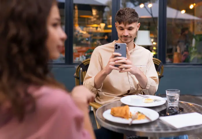 chico usando el celular mientras esta en una cita con una chica