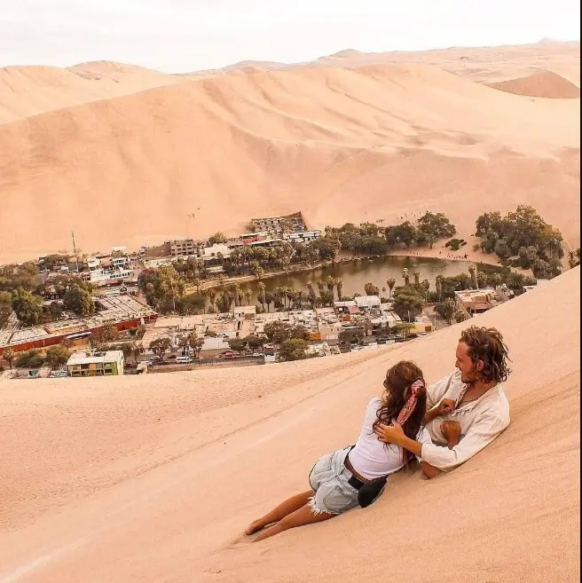 novios echados en la arena disfrutando de la vista de la huacachina